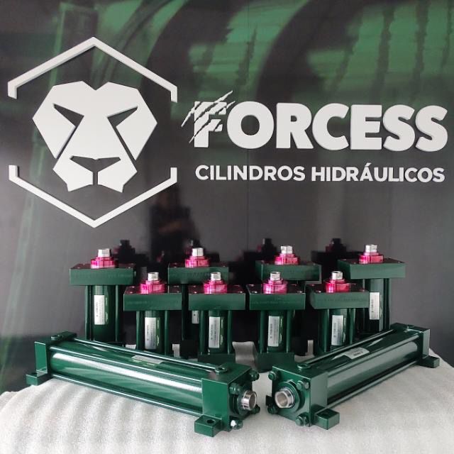 Cilindros da Forcess na frente de um painel verde contendo o logo da Forcess